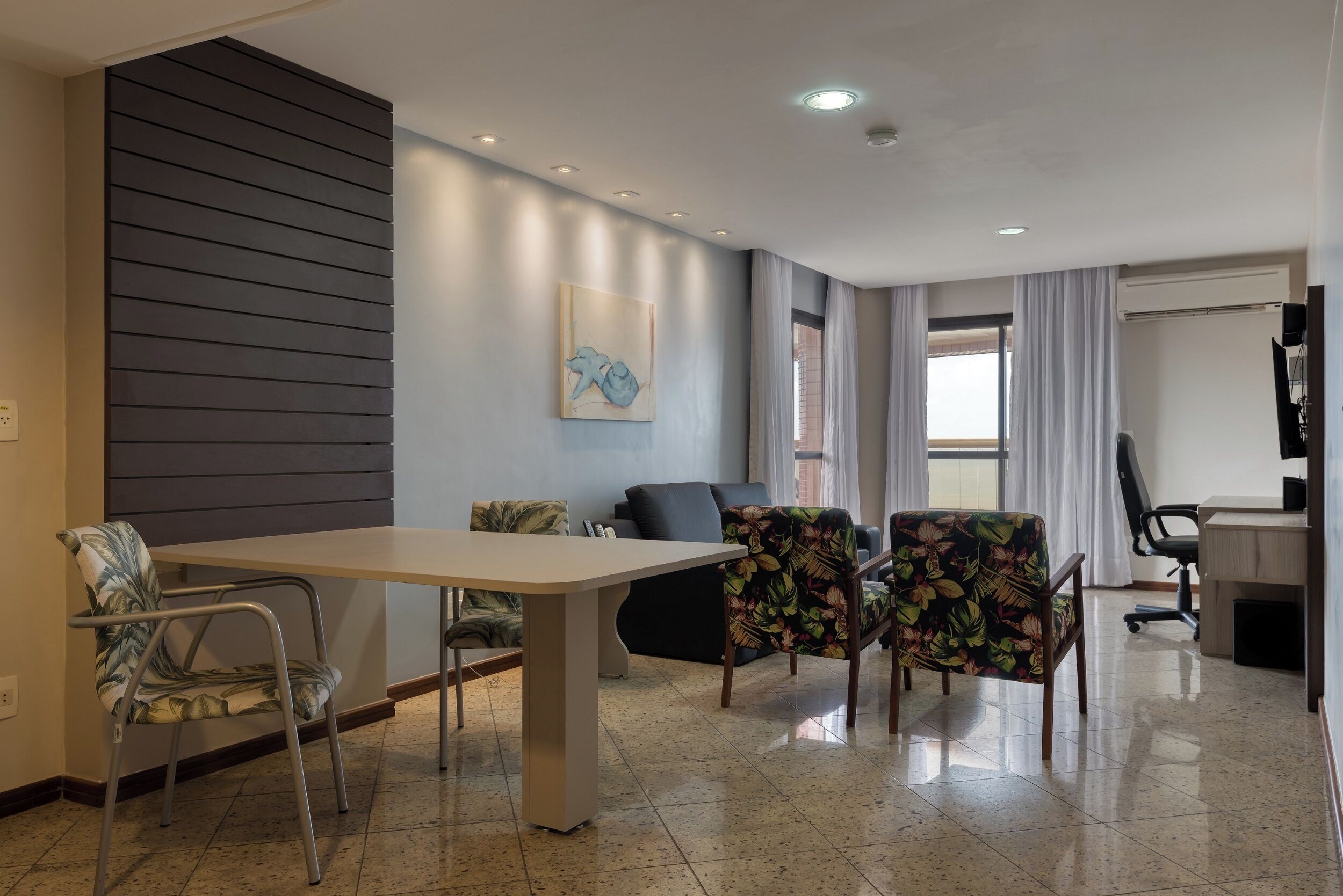 Una habitación de hotel moderna con una mesa de comedor, dos sillas, un sofá y un televisor.