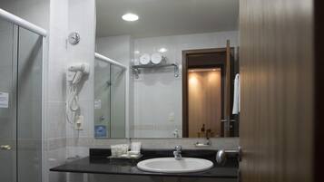 Casa de banho moderna com um espelho grande, lavatório e secador de cabelo na parede.