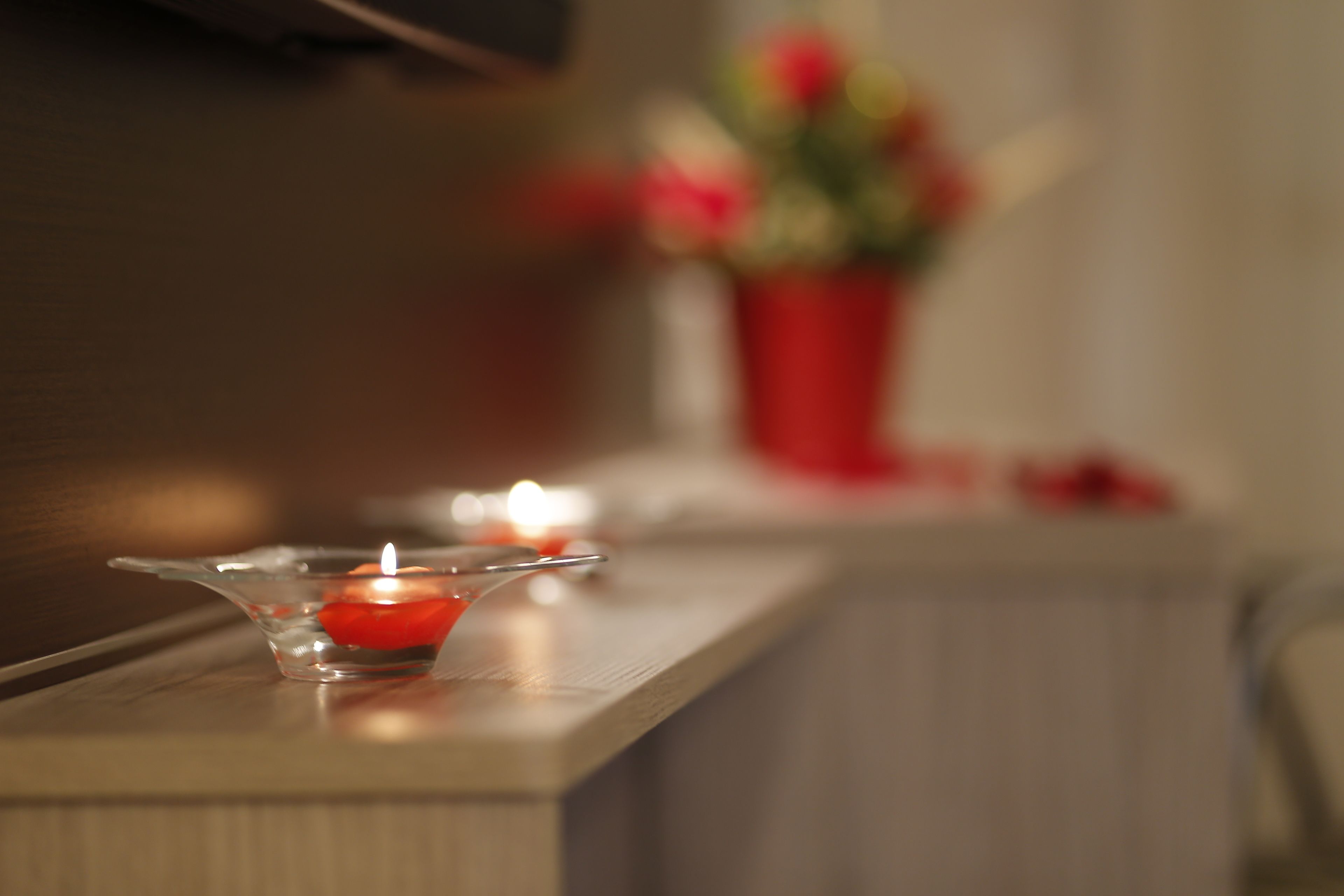 A candle in a glass holder on a wooden surface.