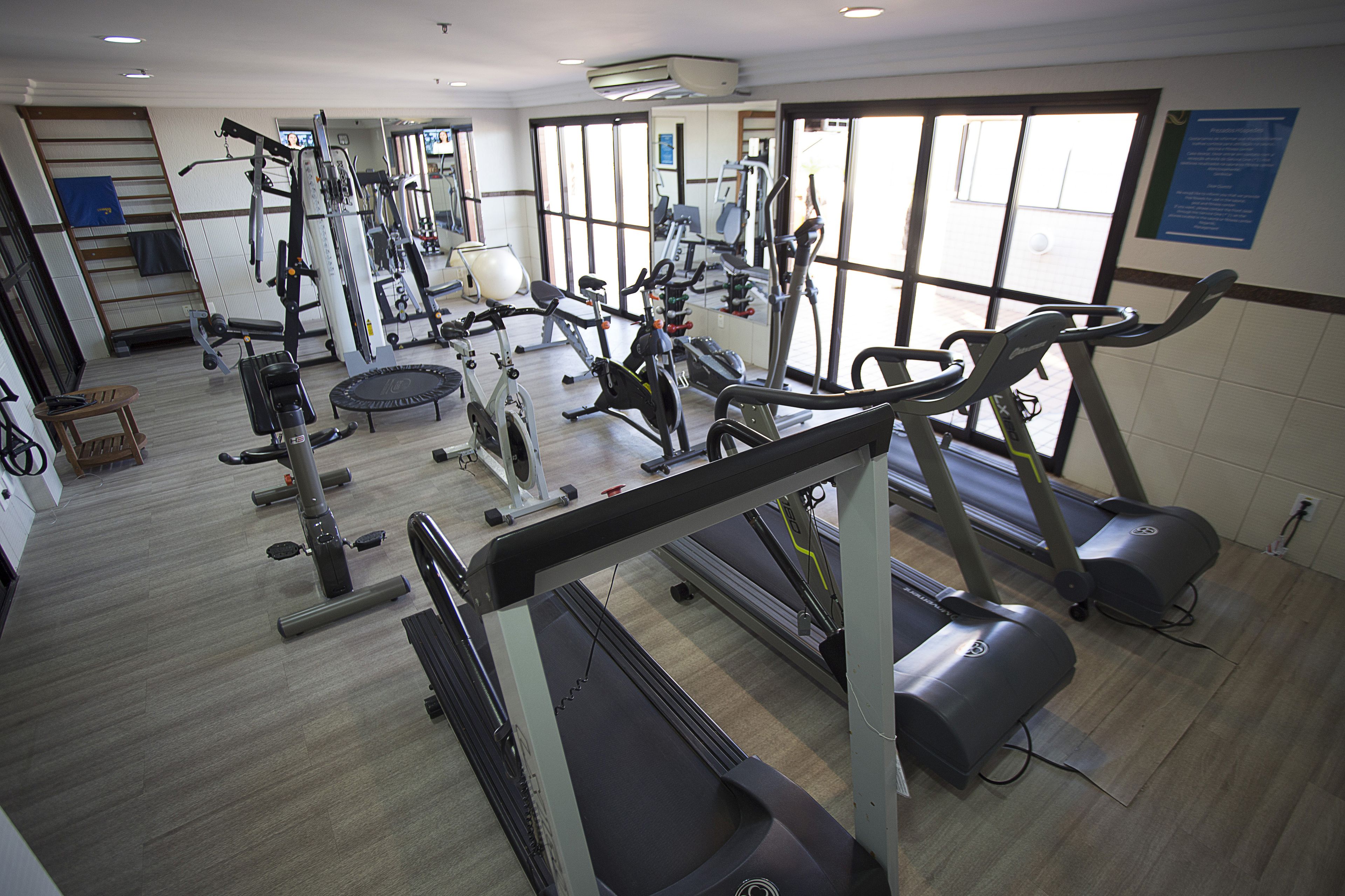 Un gimnasio con equipo de ejercicio diverso, incluyendo cintas de correr y máquinas de pesas.