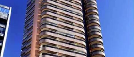 A high-rise hotel with multiple balconies and a sign reading "Quality Suites Water Plaza".