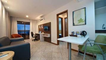 Une chambre d’hôtel équipée d’un canapé, d’un bureau, d’une chaise, d’une télévision et d’une fenêtre donnant sur un paysage agréable.