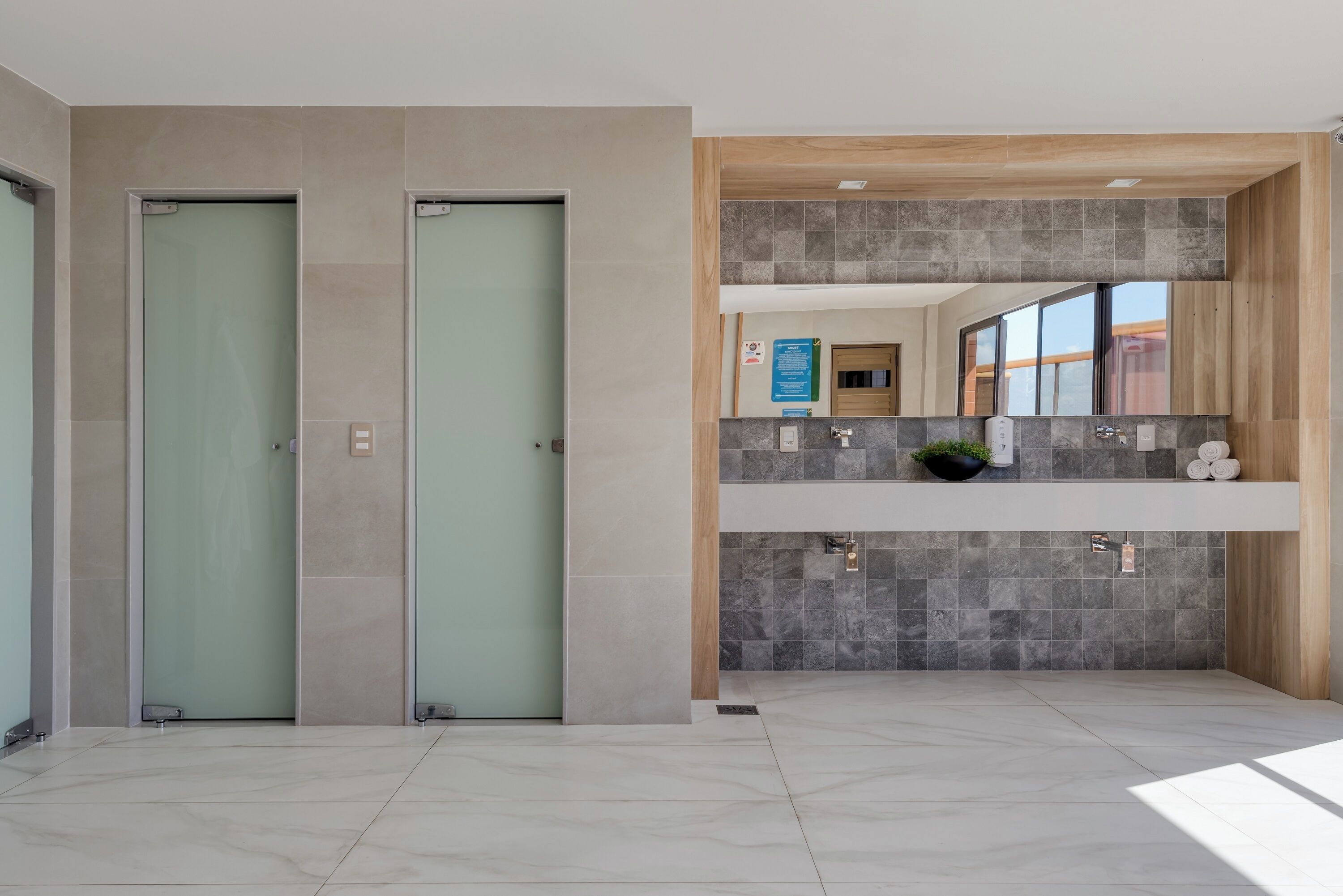 Un bany modern amb dues portes de vidre, un lavabo amb mirall i una zona de dutxa.