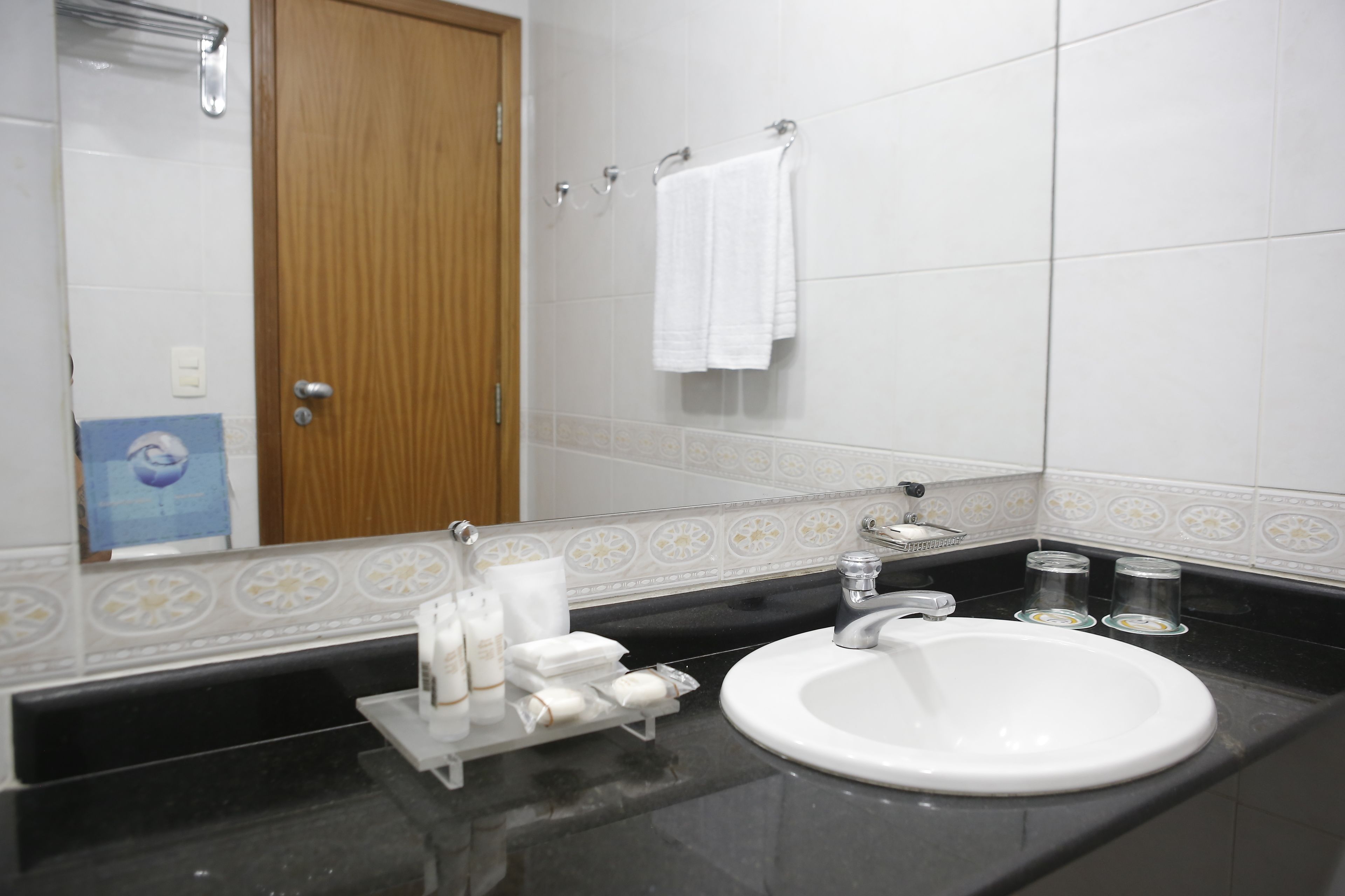 A bathroom with a white sink, a mirror, and a wooden door.