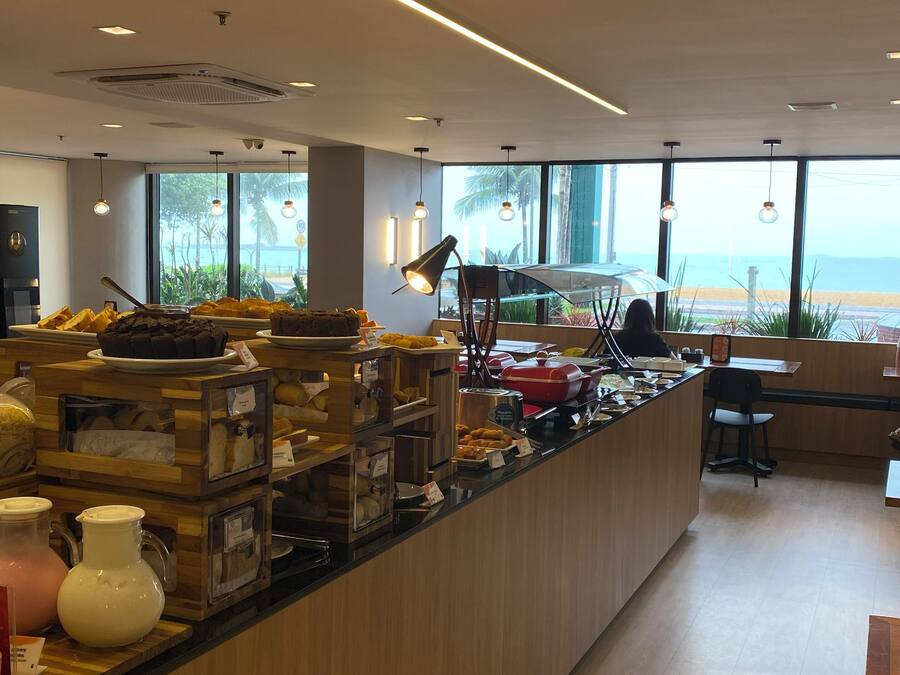 En moderne morgenmadsbar med havudsigt, træbordplade og et udvalg af morgenmadsprodukter.