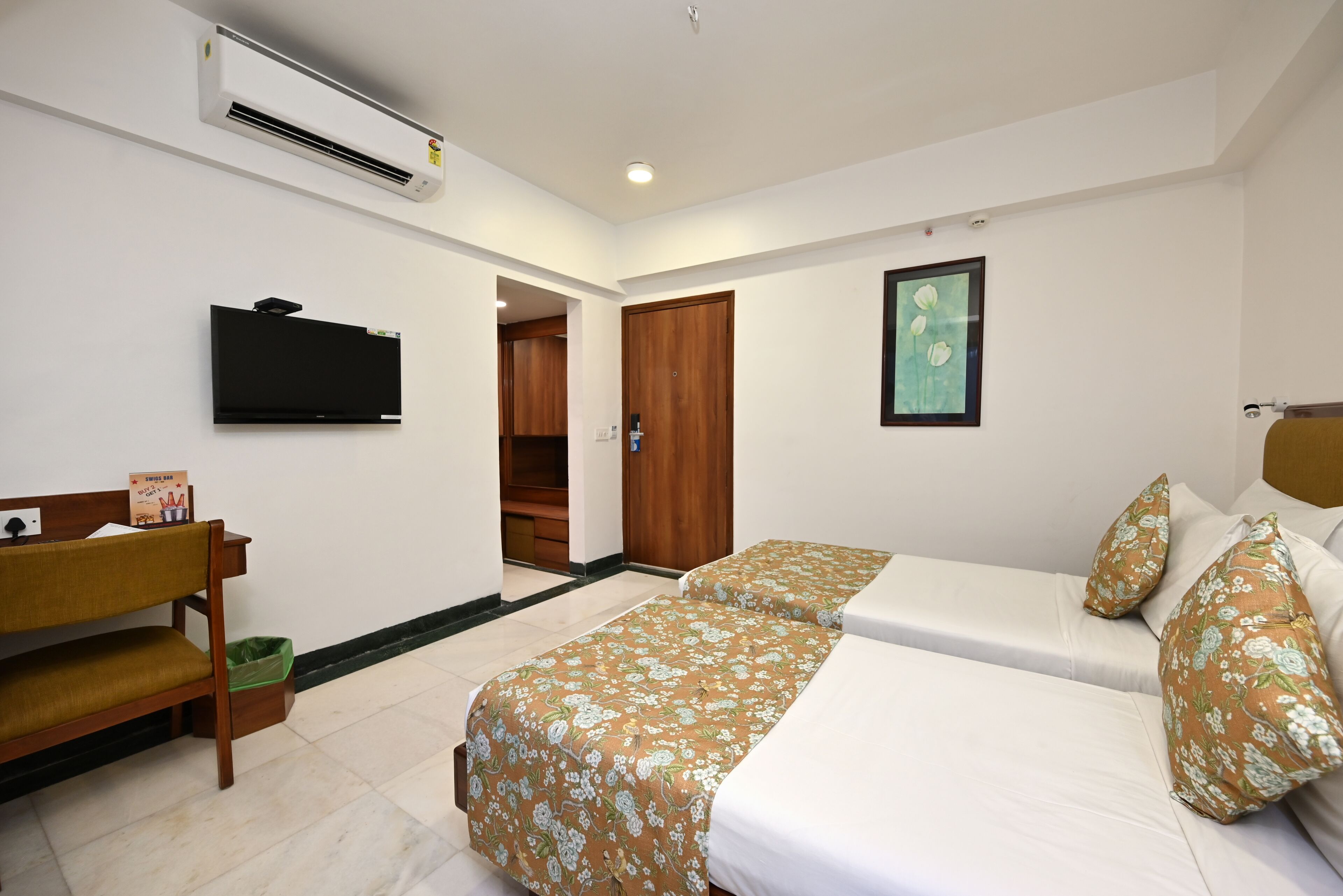 Ein Hotelzimmer mit Bett, Fernseher, Schreibtisch und Kleiderschrank.