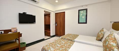 Una habitación de hotel con una cama, televisión, escritorio y armario.