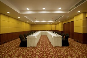 A conference room with a long table, chairs, and a patterned carpet.