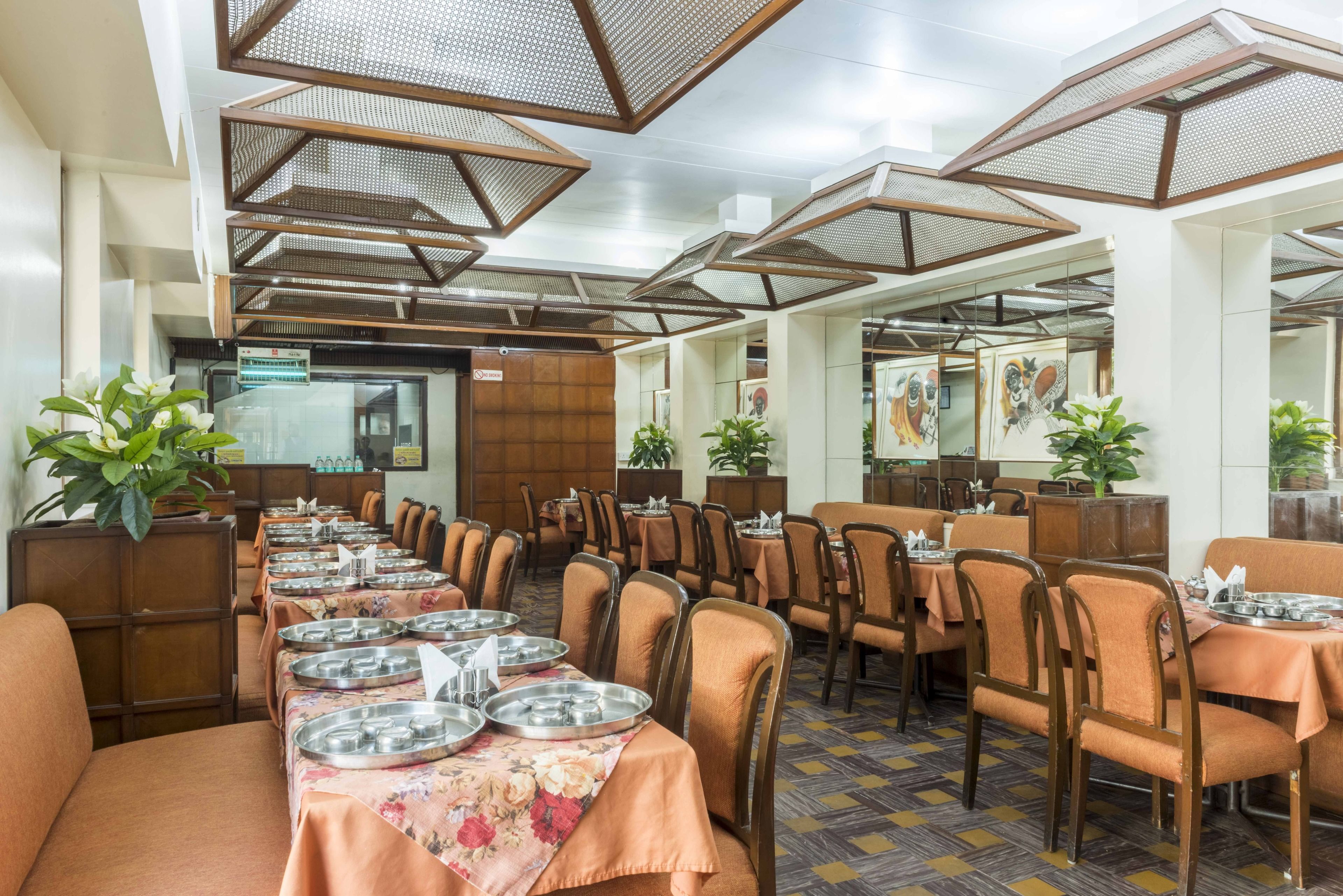 Un restaurante con mesas largas dispuestas para comer, sillas de madera y ventiladores de techo colgantes.