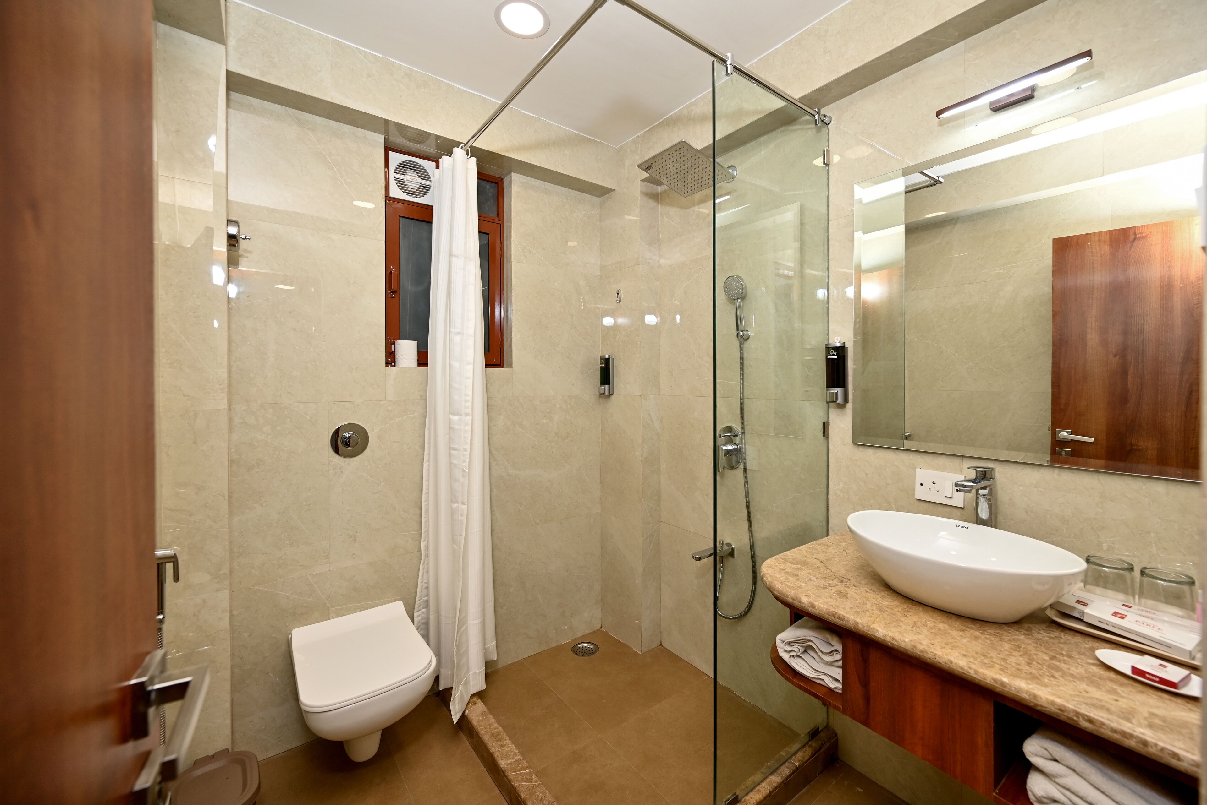 A modern bathroom with a glass-enclosed shower, a white toilet, and a vanity with a large sink and mirror.