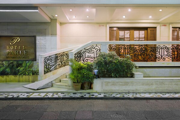 Entrada de hotel con escaleras, plantas en macetas y un letrero que dice Hotel Parle International.
