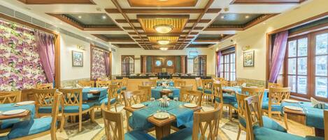 A dining area with round tables, blue tablecloths, and wooden chairs.