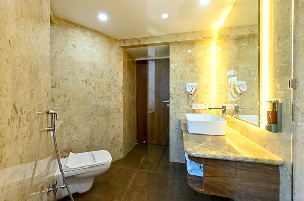 A modern bathroom with a glass partition, a white toilet, a sink with a mirror, and a hairdryer.