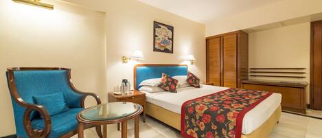 Une chambre d’hôtel avec un lit, une chaise, une petite table et une table de chevet.