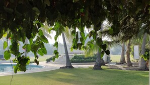 A table set outdoors with a view of the sea, covered with a white tablecloth, and surrounded by chairs. - The Meadows Resort and Spa (Chhatrapati Sambhajinagar)
