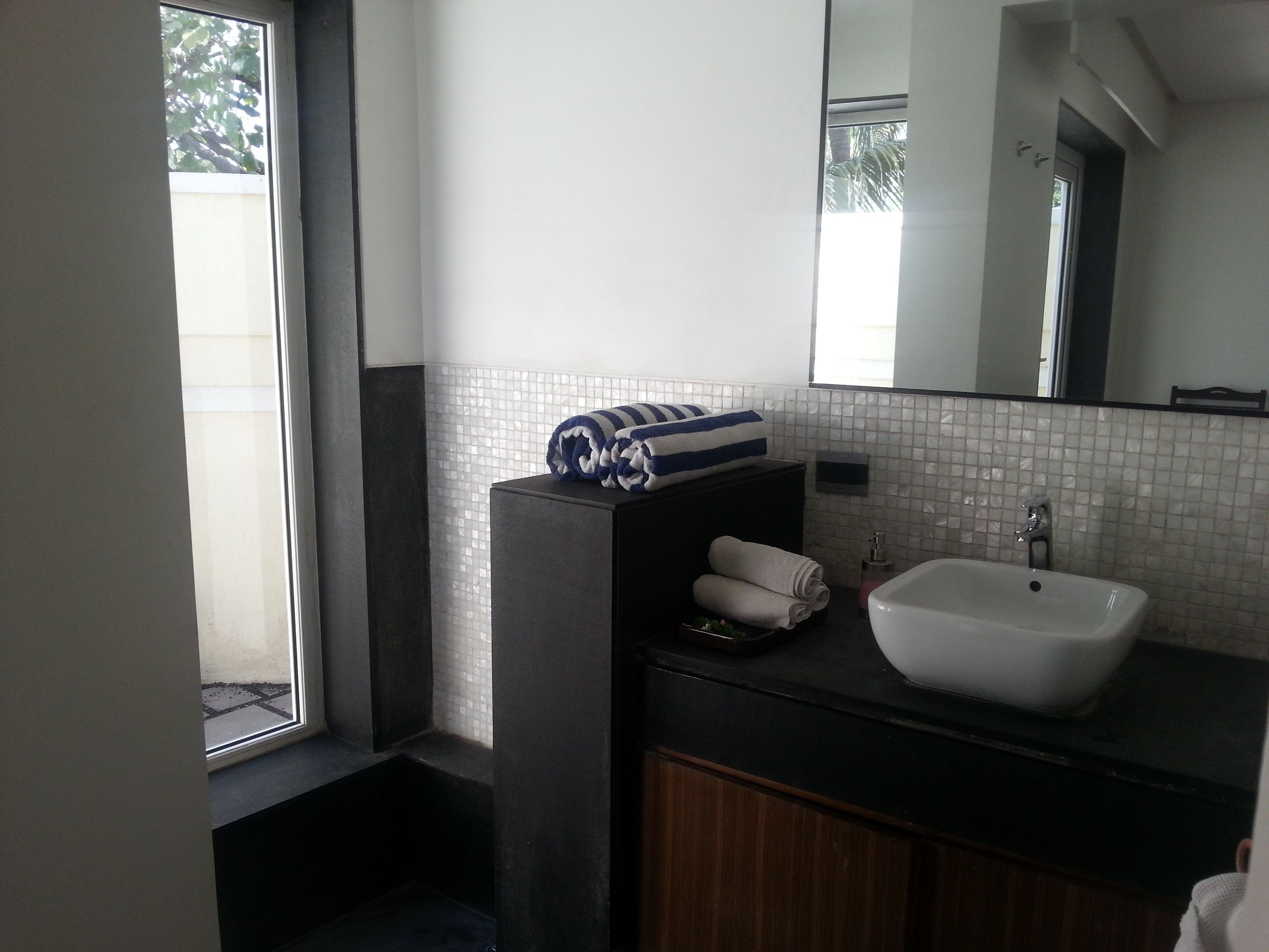 A bathroom with a black vanity, white sink, and a mirror above it.