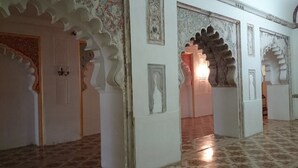 A corridor with ornate arches and a patterned floor, leading to a room with a visible door. - The Meadows Resort and Spa (Chhatrapati Sambhajinagar)