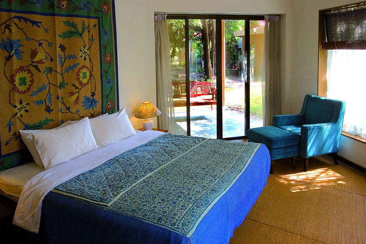 Une chambre d’hôtel avec un lit, une chaise, une lampe et une vue sur l’extérieur grâce à une porte coulissante.