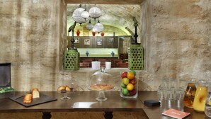 A breakfast bar with bread, pastries, and a fruit bowl. - Hôtel R. Kipling by Happyculture (Paris)