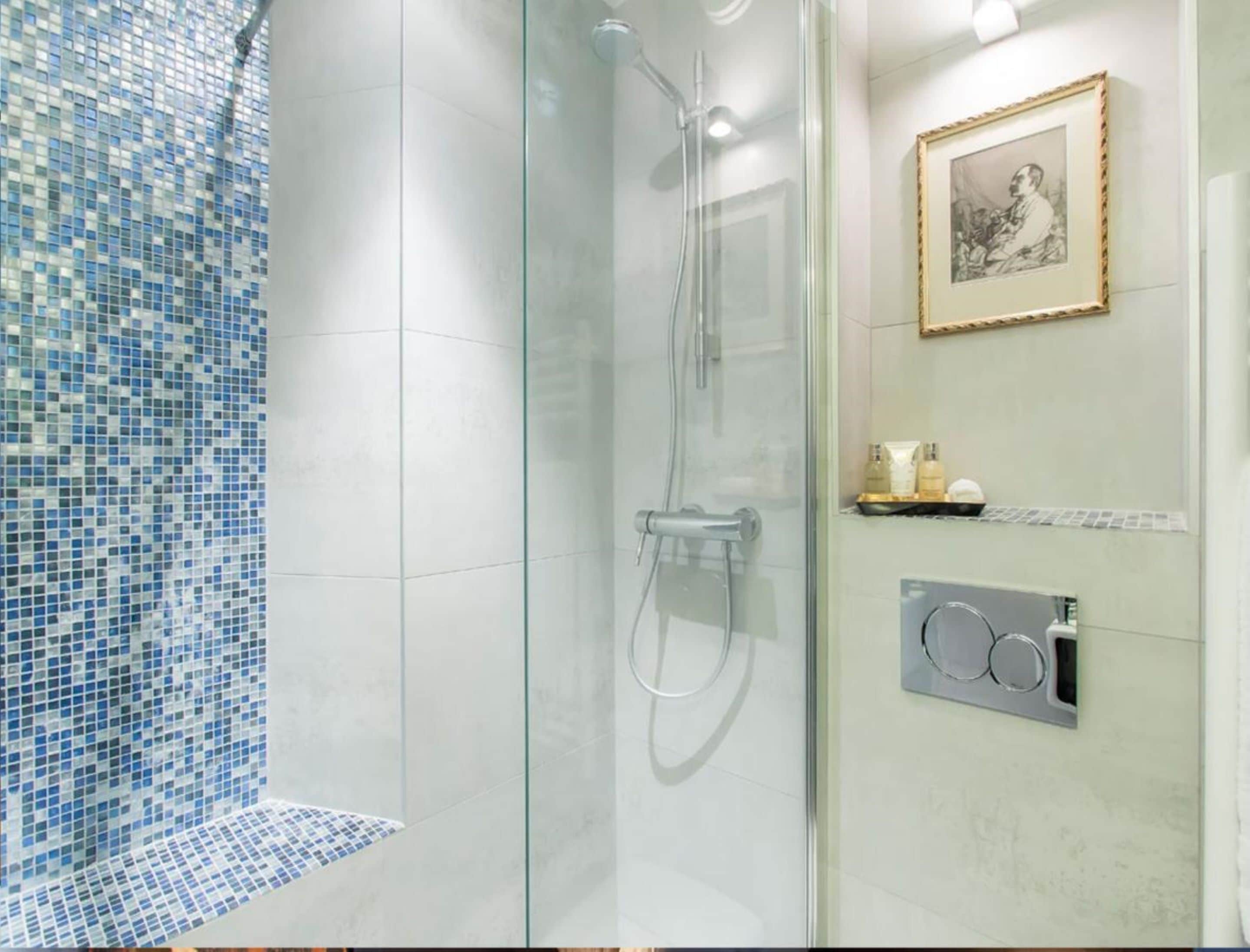 Un baño moderno con cabina de ducha de vidrio, pared con mosaico de azulejos, un cuadro enmarcado y calefacción integrada.