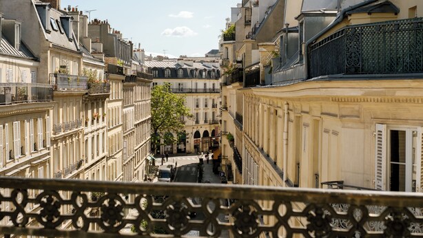 A narrow street with buildings on either side, balconies, and a clear sky. - Hôtel R. Kipling by Happyculture (Paris)