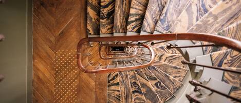 A spiral staircase with a wooden handrail and patterned carpet.