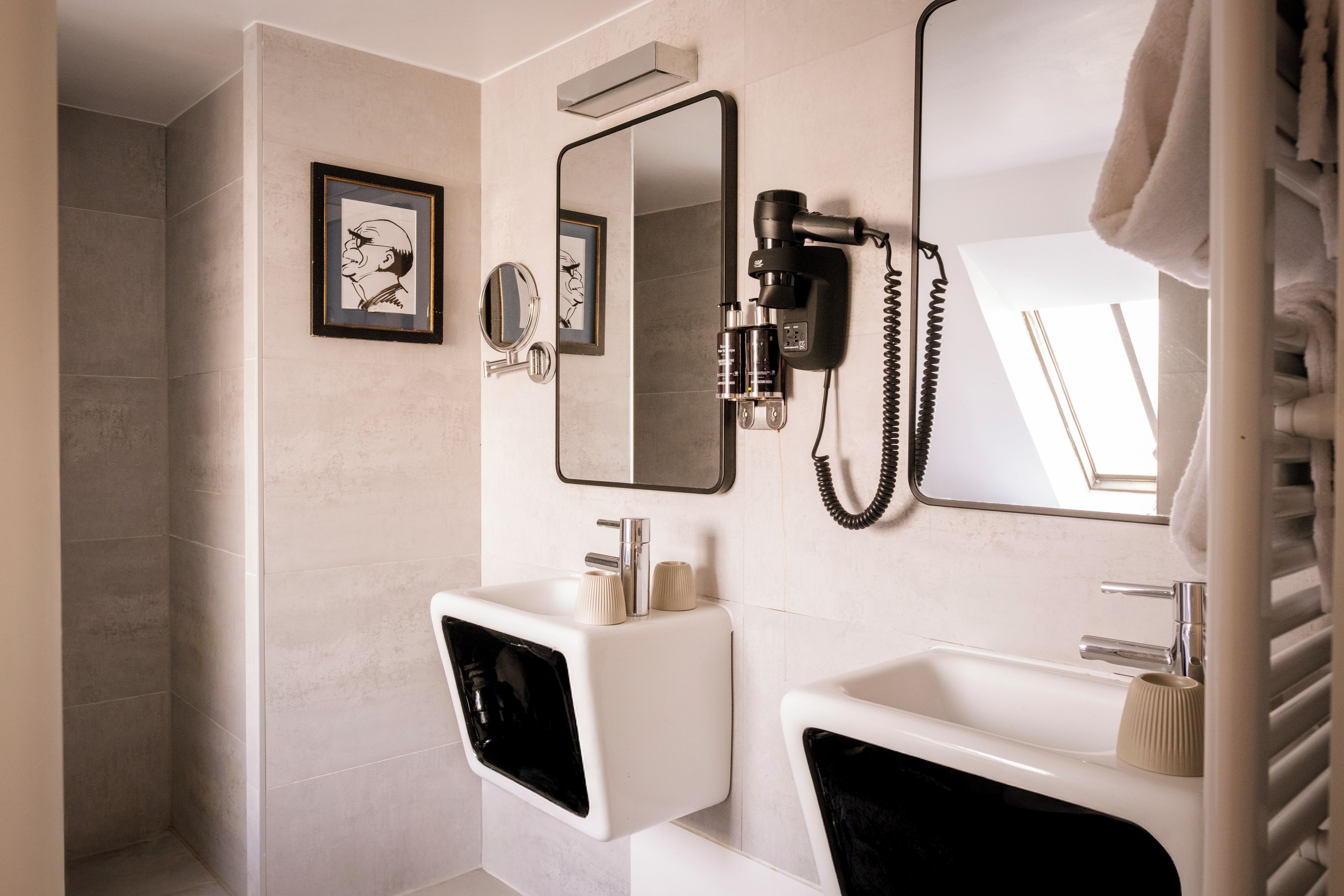 Un baño con un lavamanos blanco, un espejo y un secador de pelo montado en la pared.