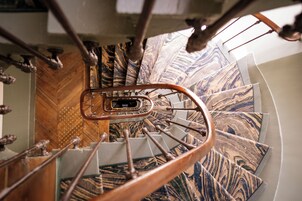 A spiral staircase with a marble-like pattern on the steps and a metal handrail.