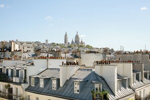A cityscape with multiple rooftops, a prominent church with two domes, and a clear sky. - Hôtel R. Kipling by Happyculture (Paris)