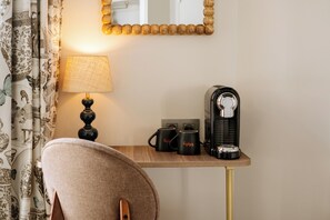 A hotel room with a desk, a lamp, two mugs, a coffee maker, and a chair. - Hôtel R. Kipling by Happyculture (Paris)