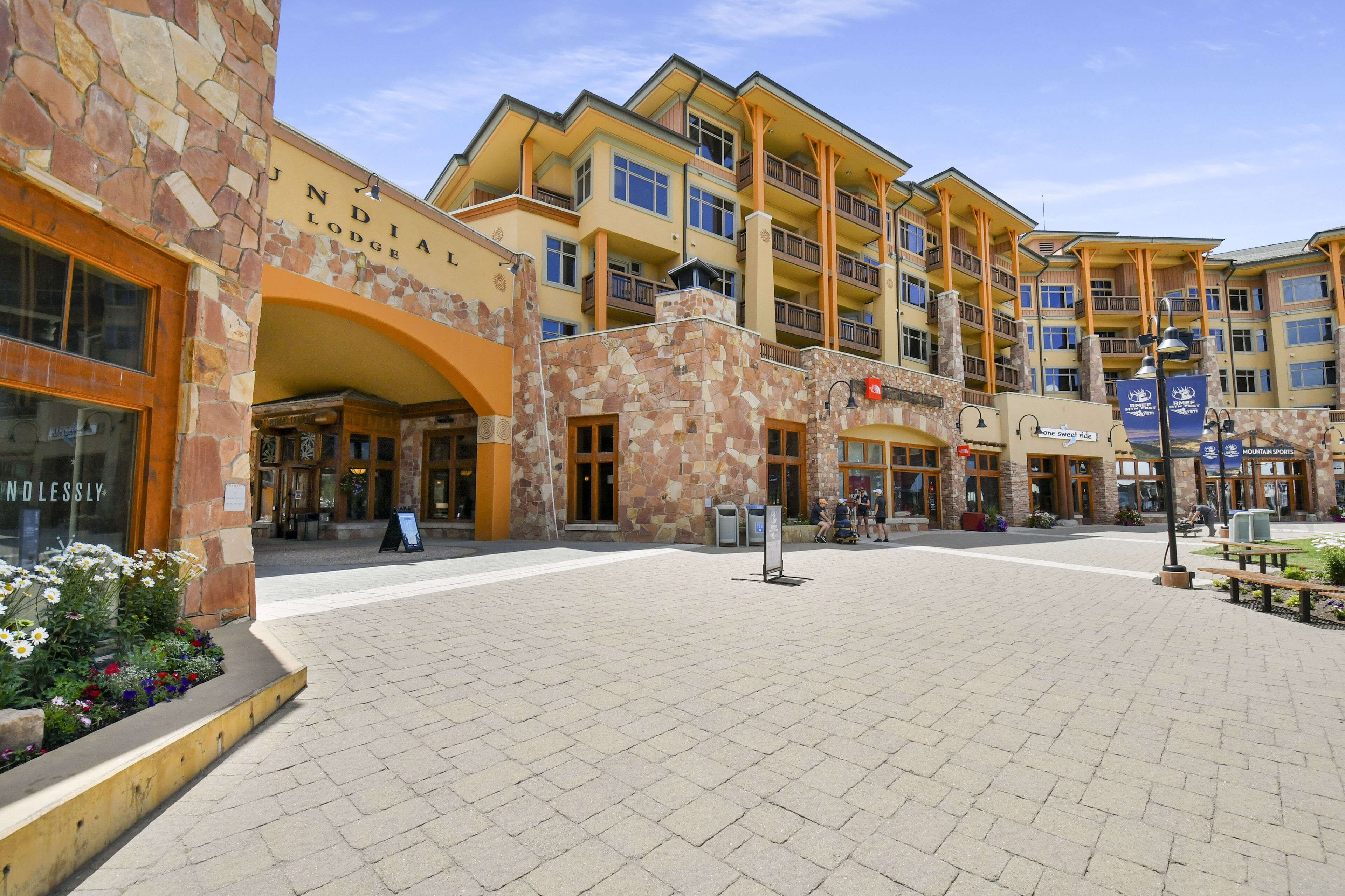 A multi-story hotel with a stone facade, multiple balconies, and a central courtyard with a bench and a signboard.