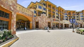 A multi-story hotel with a stone facade, multiple balconies, and a central courtyard with a bench and a signboard.