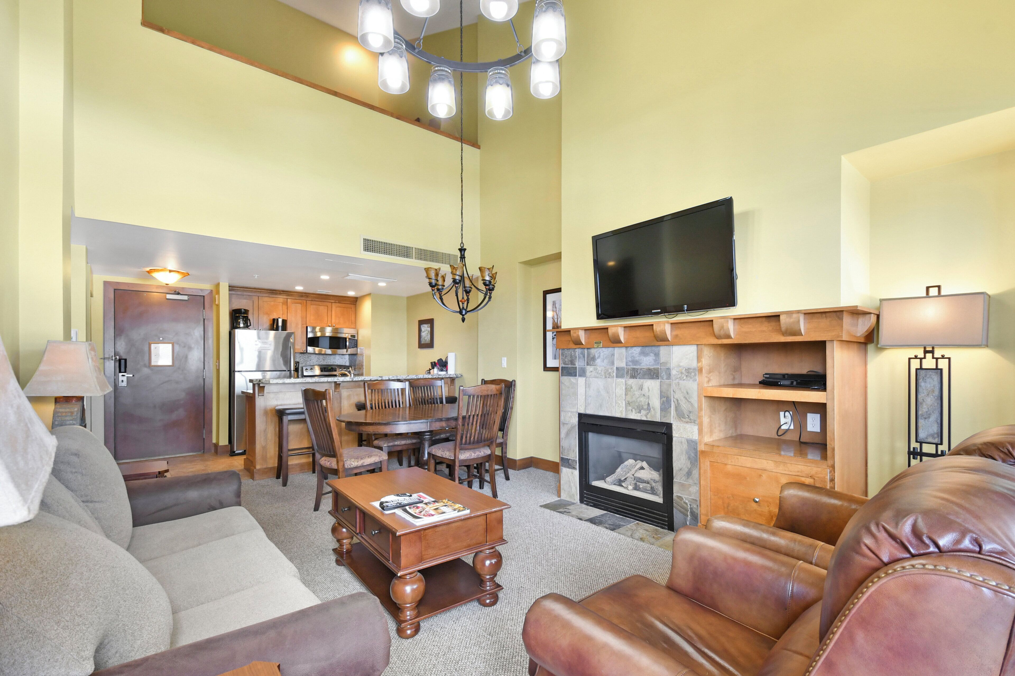 A spacious living room with a fireplace, leather sofas, a coffee table, and a television.