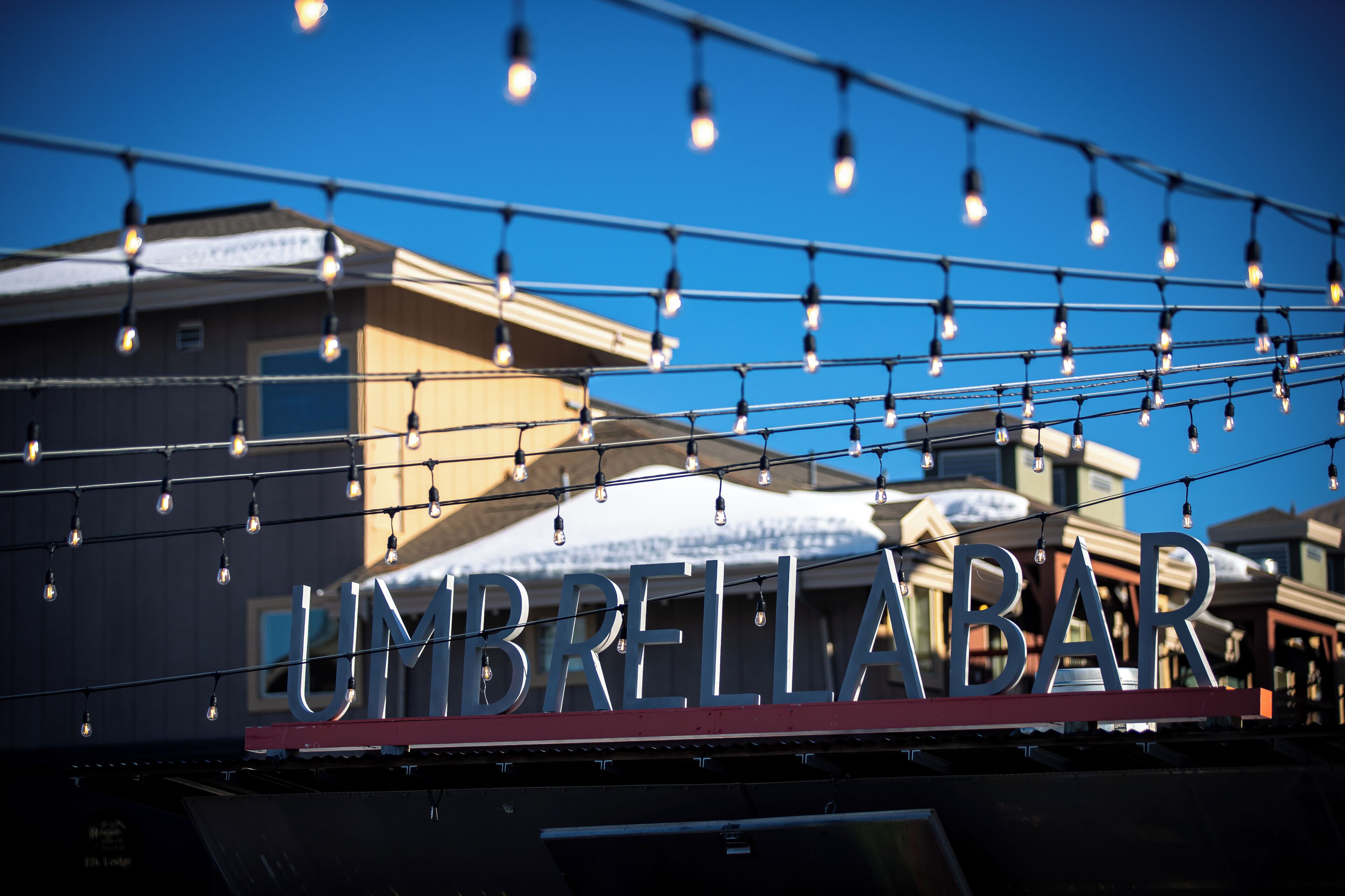 Schild für 'UMBRELLA BAR' mit freier Sicht auf die Außenfassade des Gebäudes und einer Lichterkette darüber.