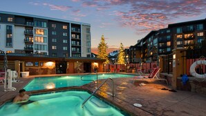 A swimming pool area with a stone deck, a lifebuoy, and a Christmas tree.