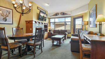 Una sala de estar con una mesa de comedor, sillas, un sofá, una mesa de centro y un televisor.
