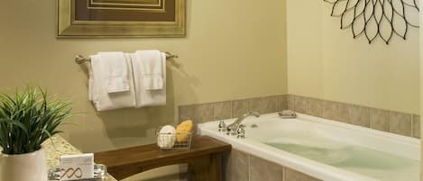 A bathroom with a bathtub, a sink, a mirror, a framed painting, and a decorative wall piece.