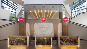 A modern reception area with a marble reception desk, glass walls, and a staircase.