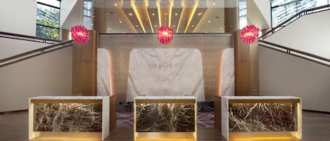 A modern reception area with a marble reception desk, glass walls, and a staircase.
