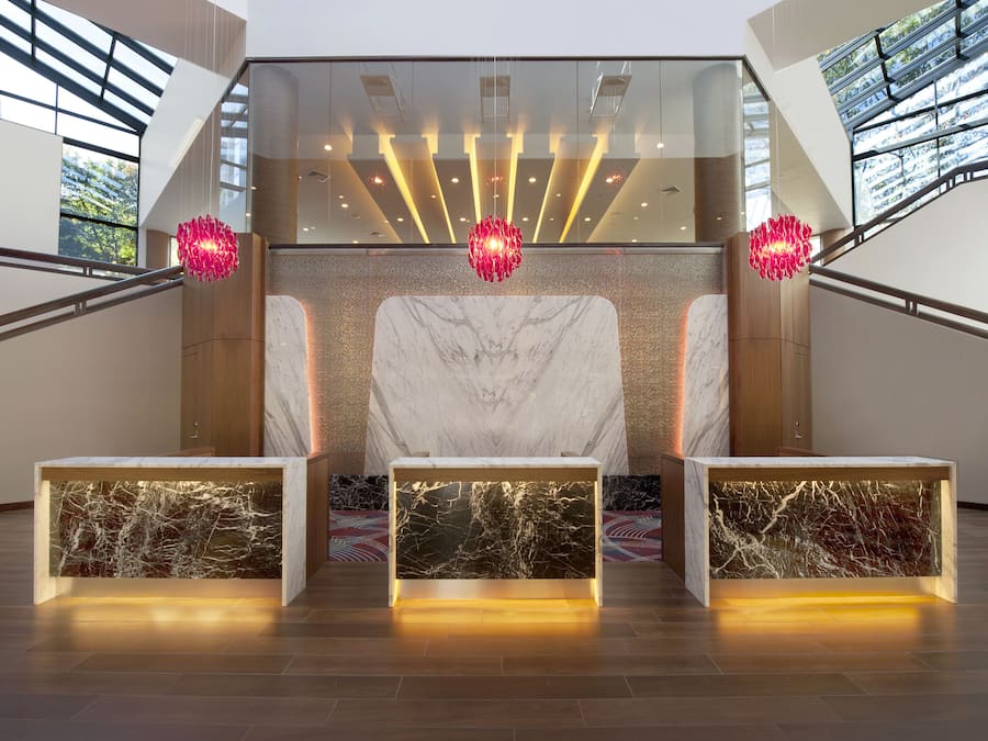 A modern reception area with a marble reception desk, glass walls, and a staircase.
