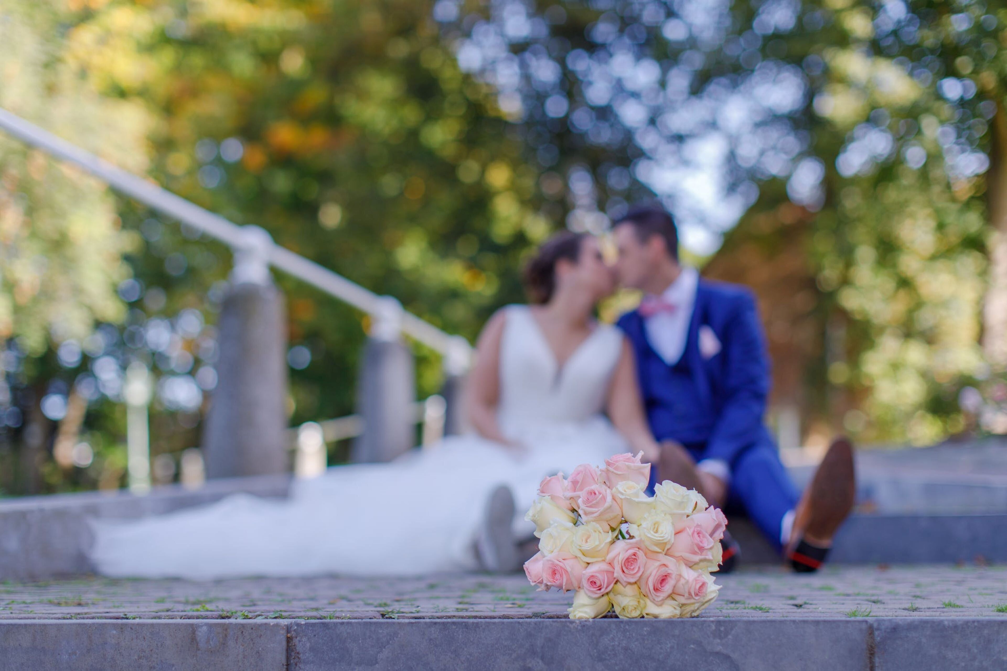A couple sitting on steps with a bouquet of flowers in front of them.