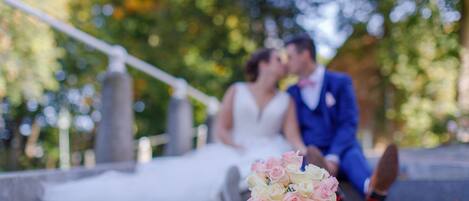 A couple sitting on steps with a bouquet of flowers in front of them.