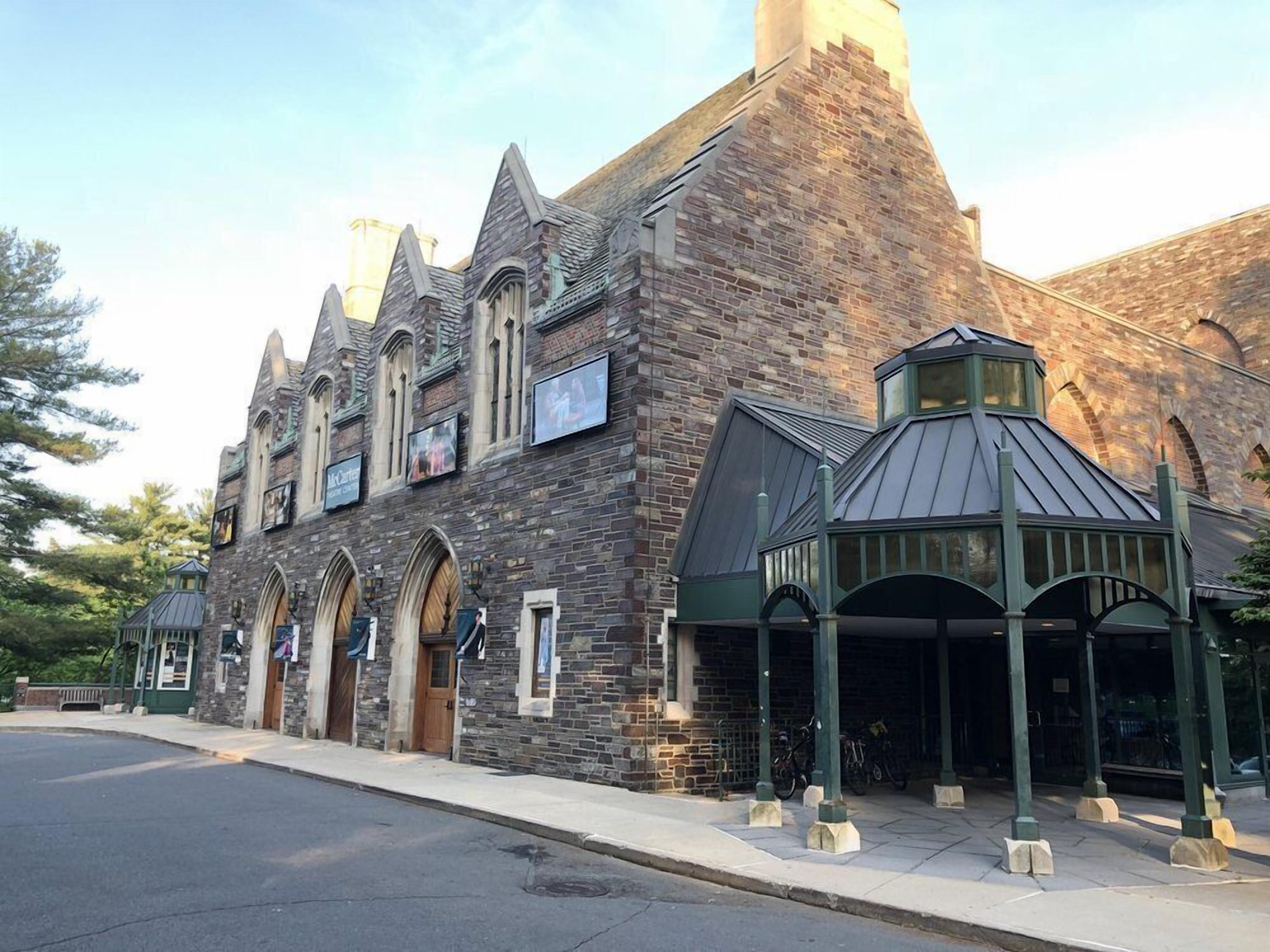 A historic building with a stone facade, arched windows, and a covered entrance area.