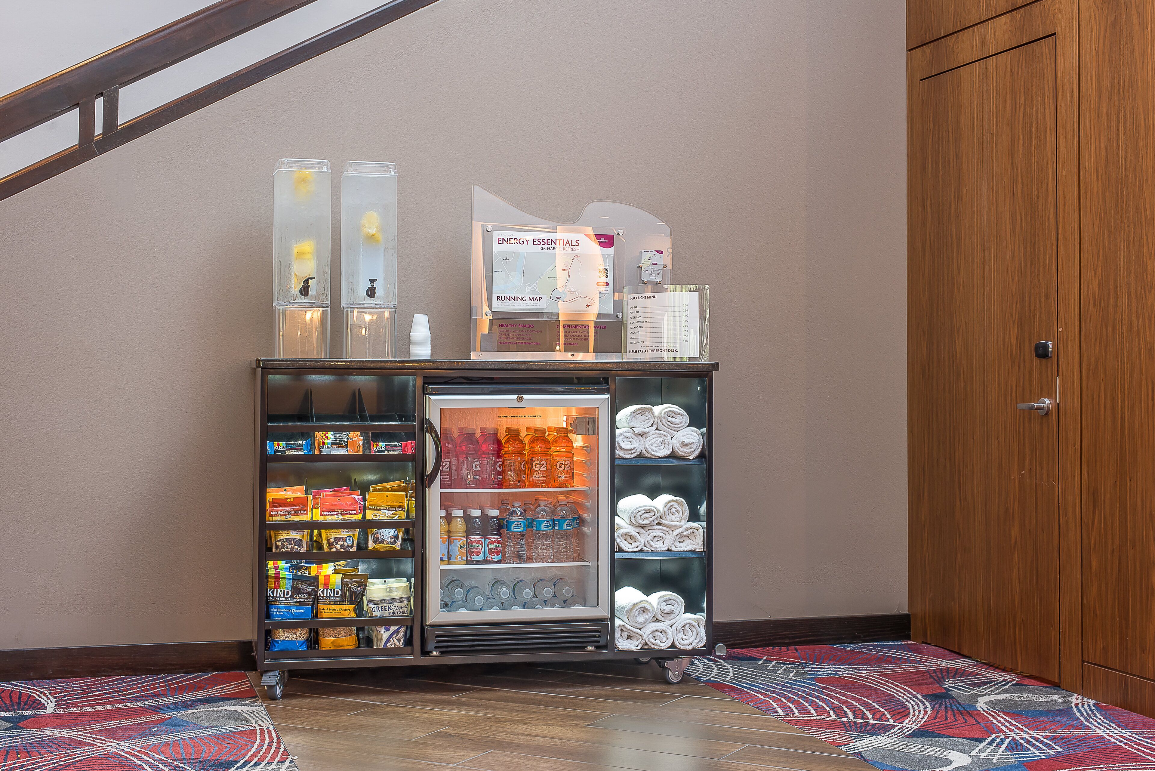 A vending machine with snacks and drinks, a refrigerator with bottled water, and a running map sign.