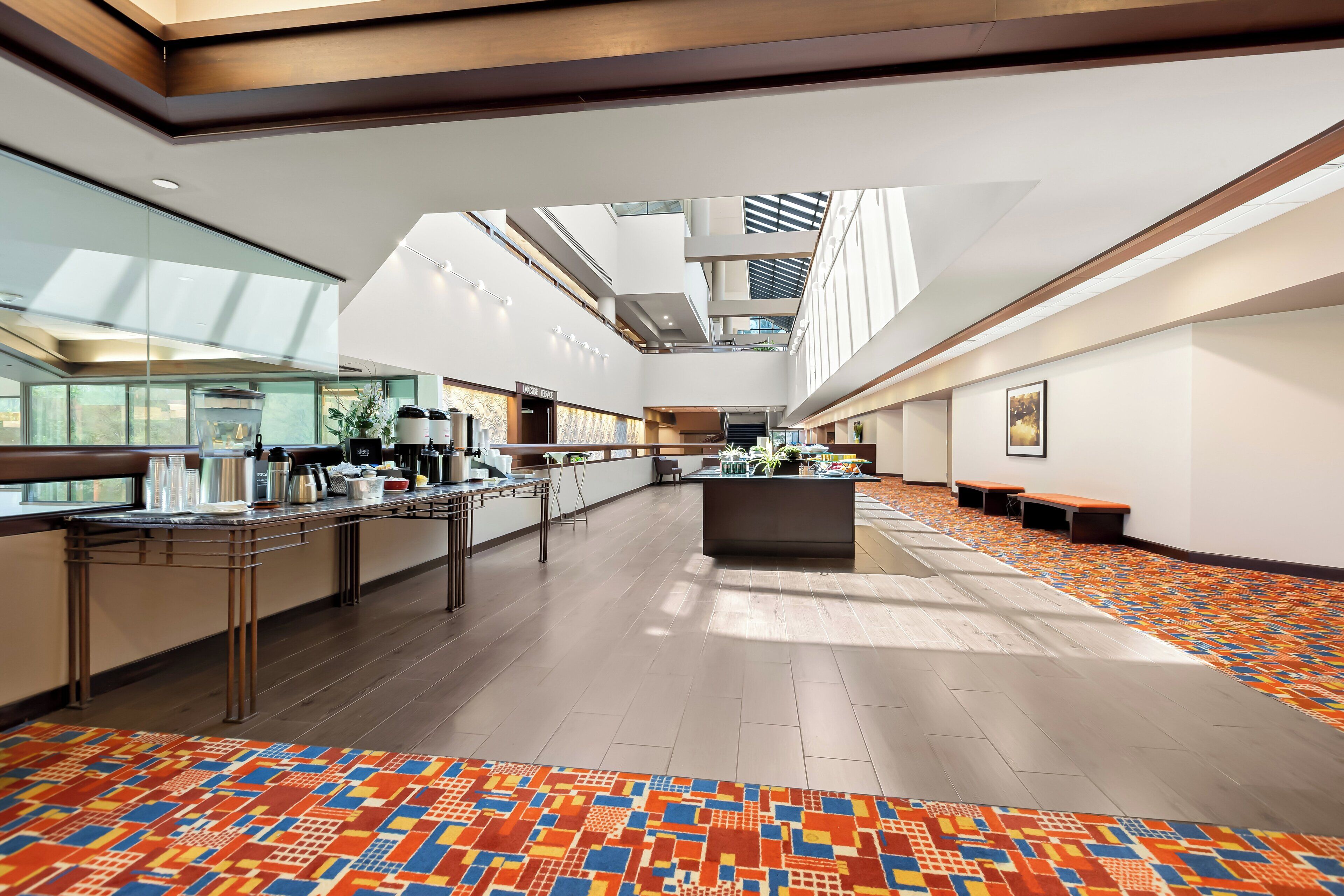 A spacious lobby with a central island, a glass wall on one side, and a patterned carpet.