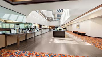 A spacious lobby with a central island, a glass wall on one side, and a patterned carpet.
