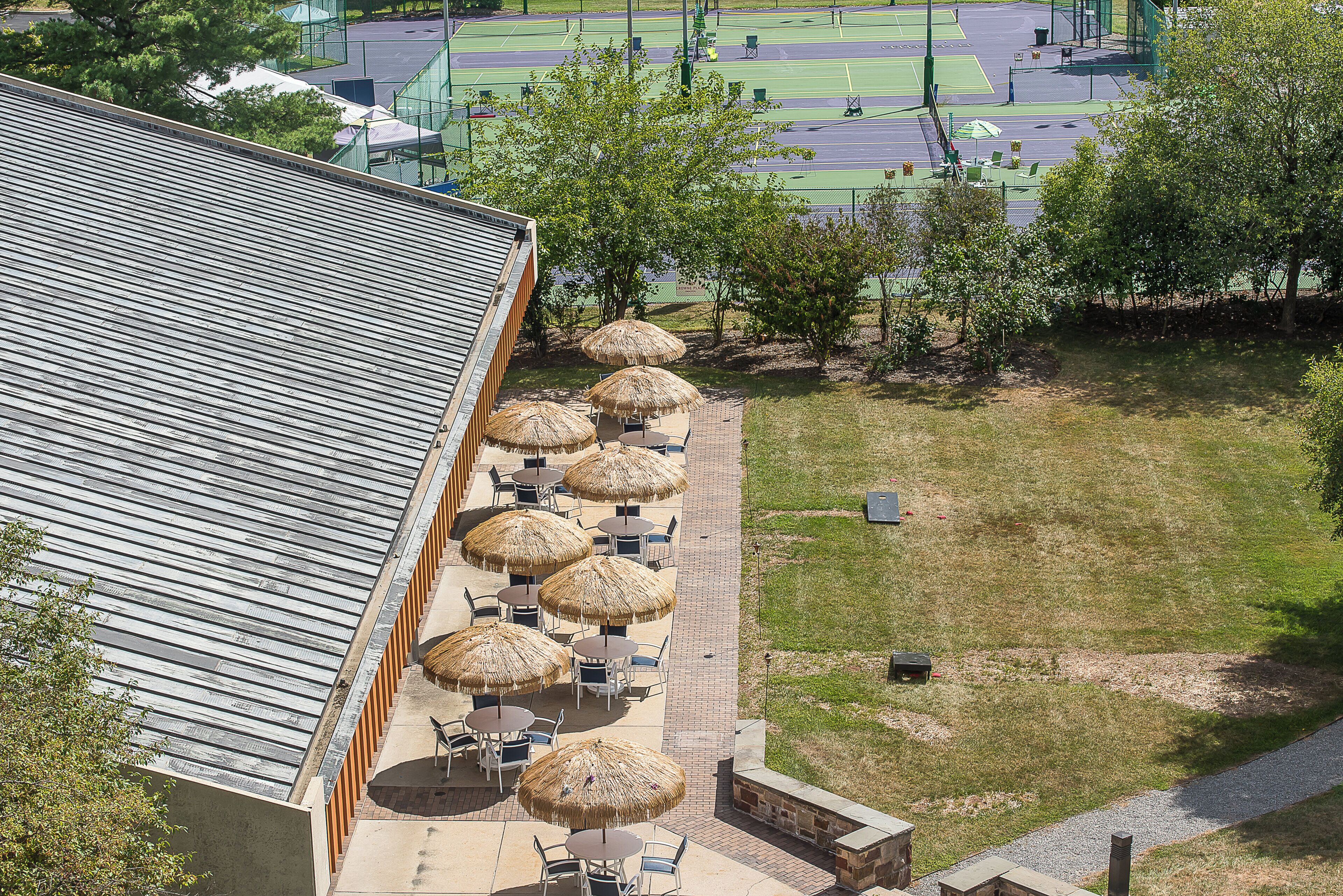 A building with a sloped roof and a patio area with thatched umbrellas and seating.