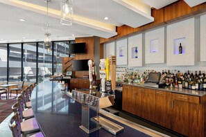 A modern bar area with a long counter, bar stools, and a variety of liquor bottles. - Crowne Plaza Princeton-Conference Center by IHG (Plainsboro)