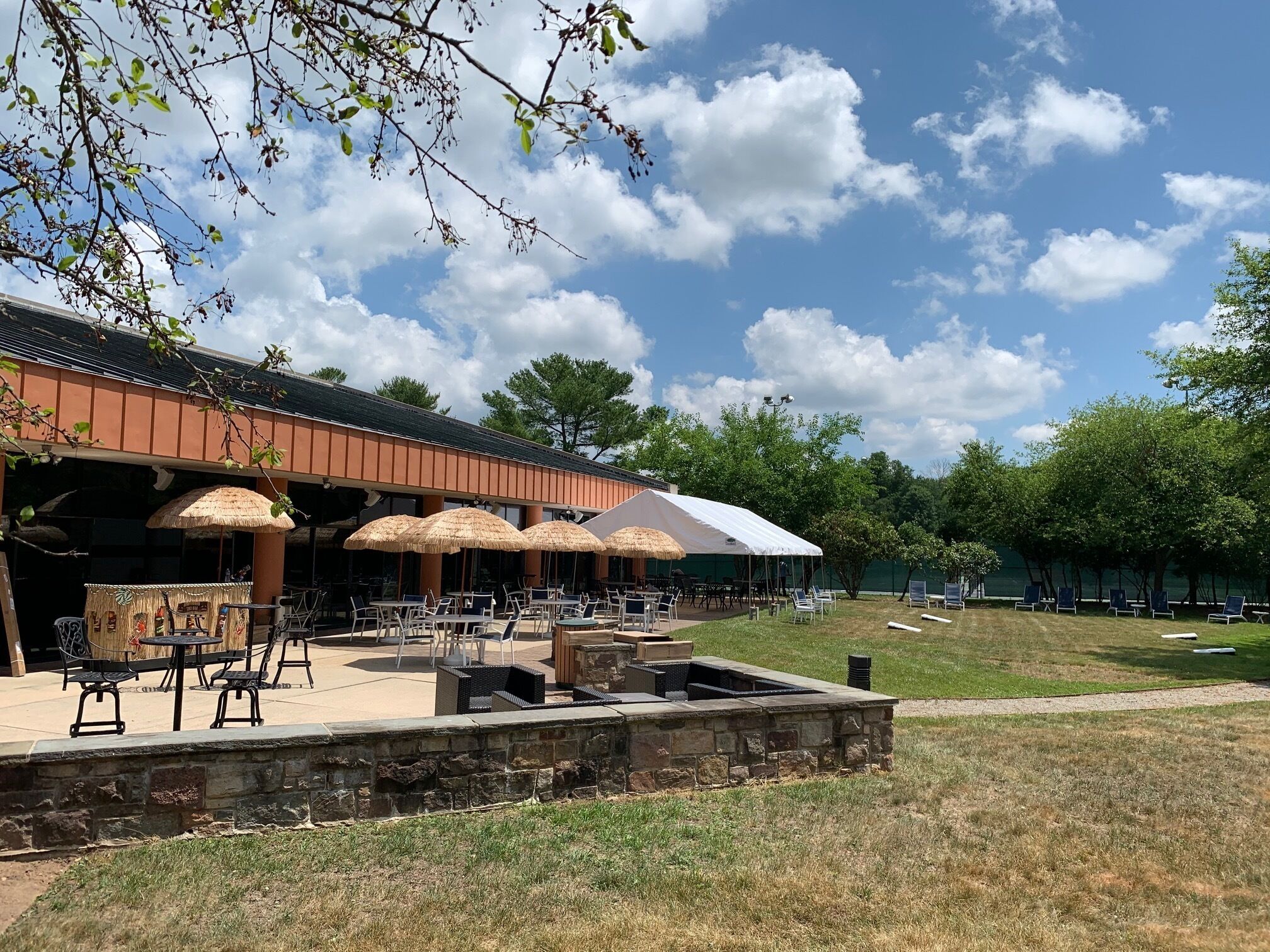An outdoor patio area with tables and chairs, a covered seating area, and a stone fire pit.
