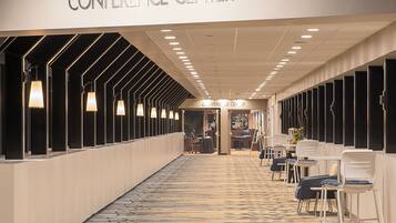A conference center with a long corridor, seating area, and a reception desk.